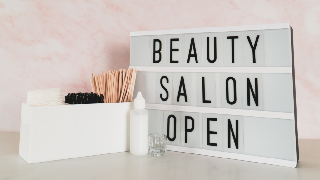 napis: beauty salon open, obok drewniane patyczki kosmetyczne